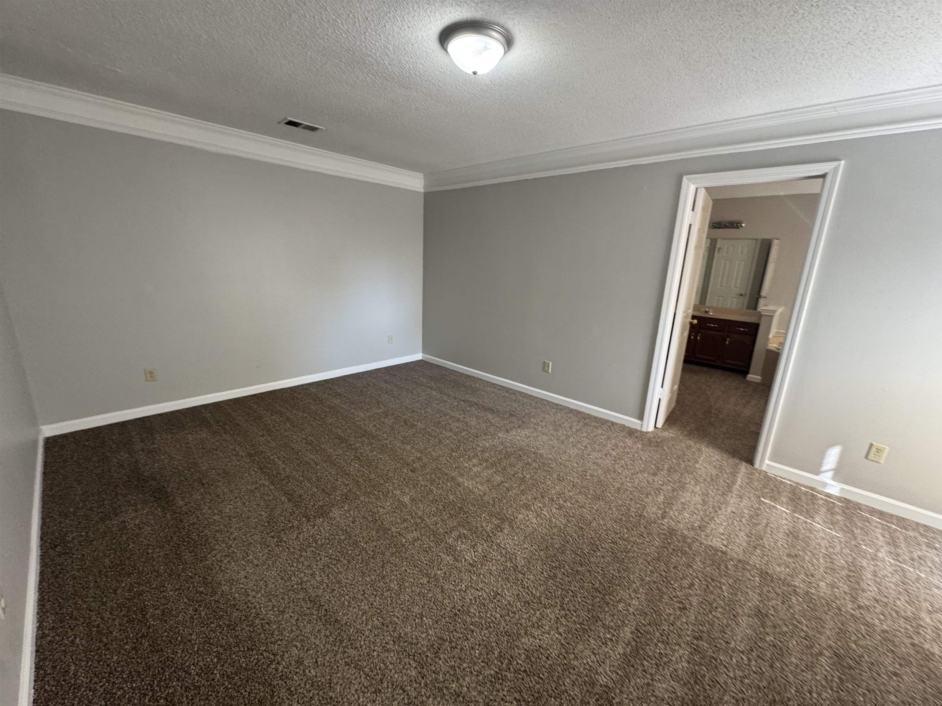 7266 Woodshire Road Memphis, TN 38125 - Photo 9 of 14 Unfurnished bedroom with crown molding, dark colored carpet, a textured ceiling, and ensuite bath