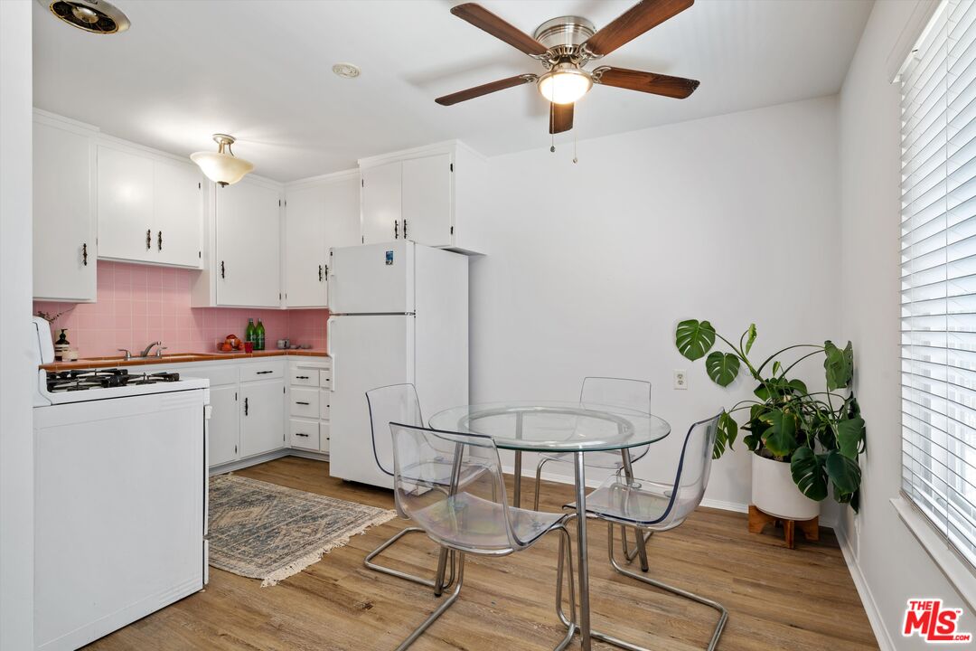 819 East 4th Street, Unit 15 Long Beach, CA 90802 - Photo 7 of 27 a kitchen with stainless steel appliances kitchen island granite countertop a table chairs in it and wooden floors