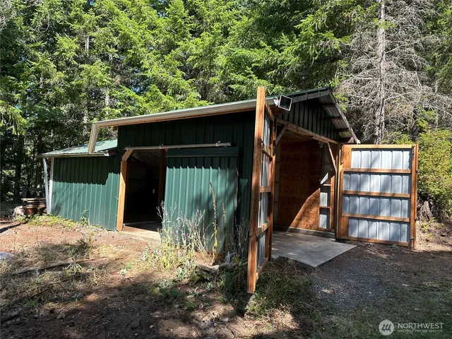a view of a wooden house with large trees and wooden fence