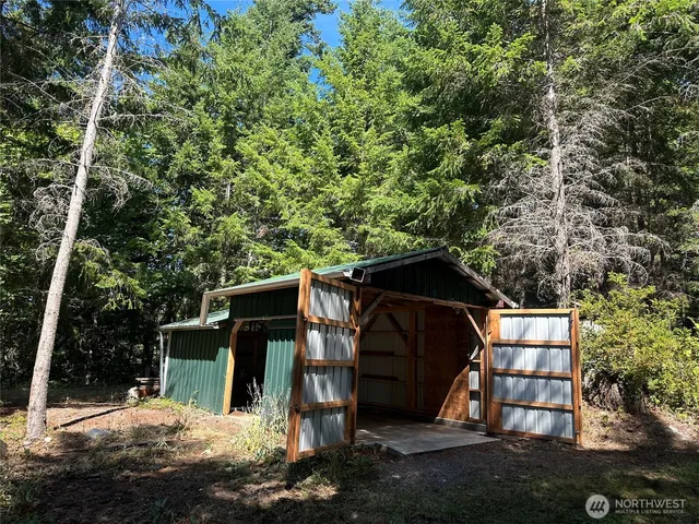 a view of a small yard in front of a house with large trees and plants
