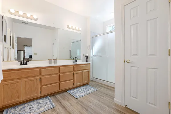 a spacious bathroom with a double vanity sink a mirror and shower