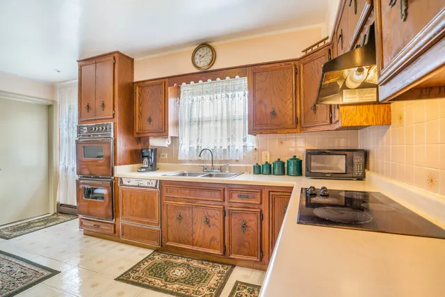 a kitchen with stainless steel appliances a sink a stove a refrigerator cabinets and a window