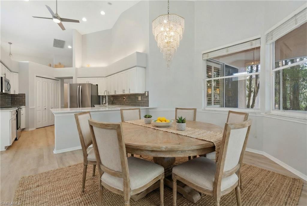 20751 Rivers Ford Estero, FL 33928 - Photo 3 of 36 Dining area featuring a ceiling fan, a towering ceiling, a chandelier, and light wood-style flooring