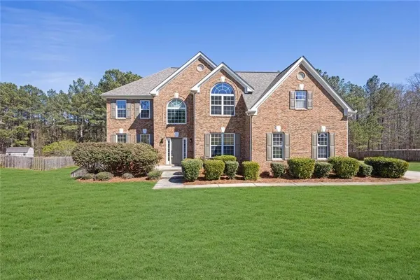 a front view of a house with a yard and trees