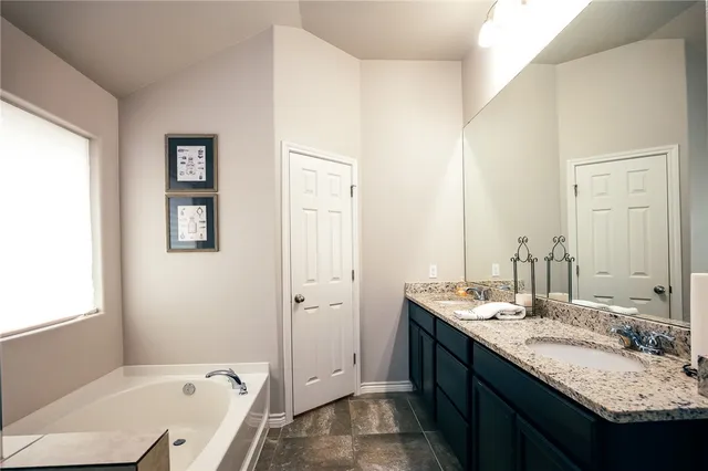 a bathroom with a granite countertop tub sink and mirror