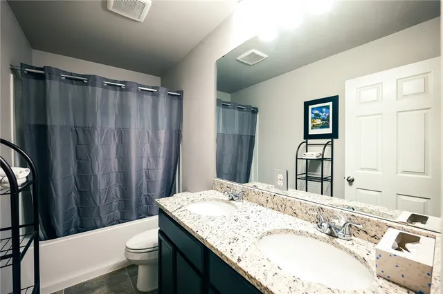 a bathroom with a granite countertop sink toilet and shower
