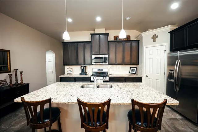 a kitchen with stainless steel appliances kitchen island granite countertop a kitchen island a table chairs and a refrigerator