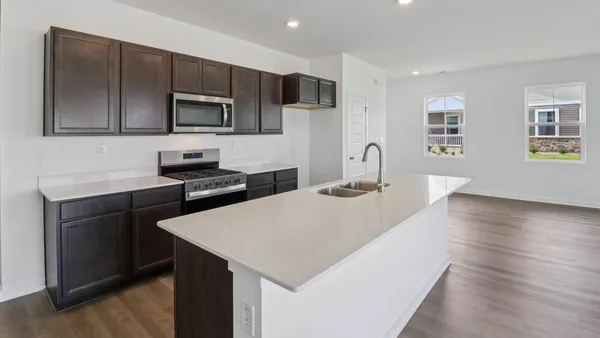 a kitchen with stainless steel appliances a sink a stove a microwave a sink a refrigerator and cabinets