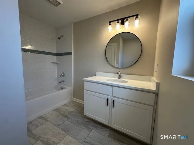 a bathroom with a sink mirror vanity and bathtub