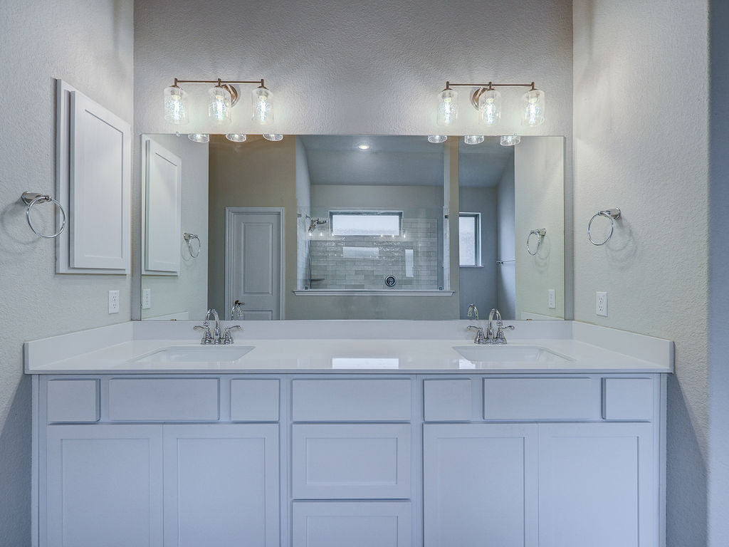 229 Heartleaf Road San Marcos, TX 78666 - Photo 27 of 40 Dual vanities with pristine countertops and chrome fixtures elevate this modern bathroom's design.