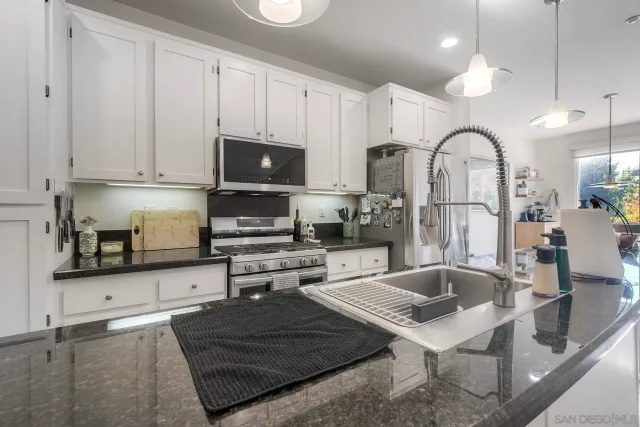 a kitchen with stainless steel appliances granite countertop a sink a stove and a wooden cabinets