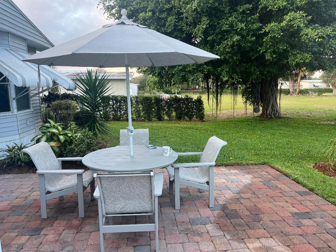 6985 Southeast Amendment Street Hobe Sound, FL 33455 - Photo 24 of 27 a view of a patio with table and chairs under an umbrella