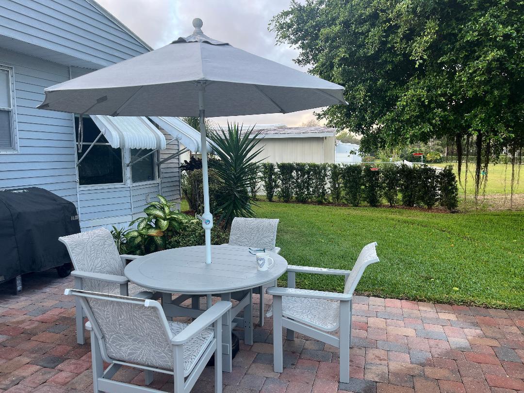 6985 Southeast Amendment Street Hobe Sound, FL 33455 - Photo 25 of 27 a patio with a table and chairs under an umbrella