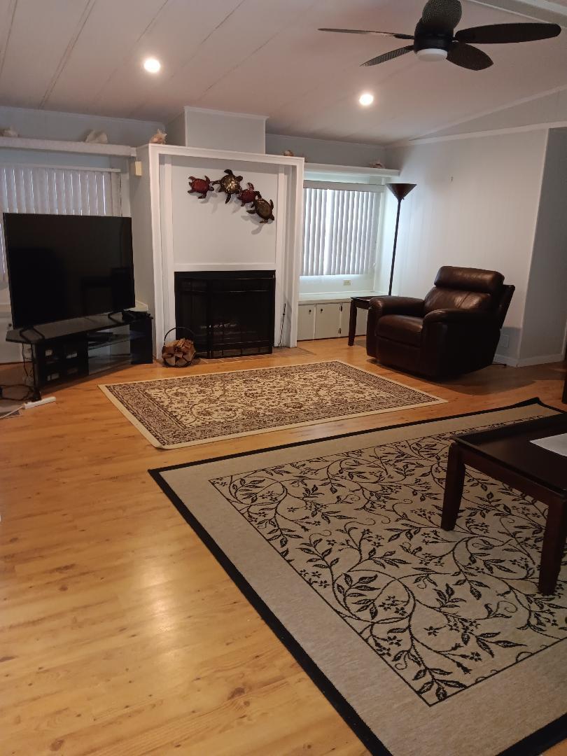 6985 Southeast Amendment Street Hobe Sound, FL 33455 - Photo 9 of 27 a living room with furniture a flat screen tv and a fireplace