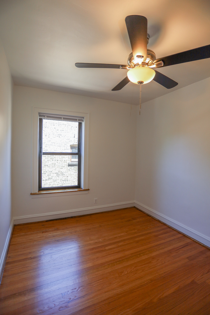 4411 North Hamilton Avenue, Unit 2W Chicago, IL 60618 - Photo 11 of 15 an empty room with wooden floor fan and windows