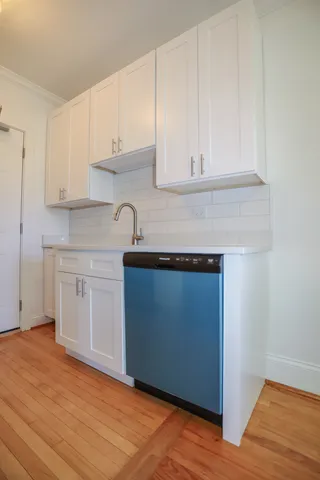 a kitchen with granite countertop white cabinets and a wooden floor