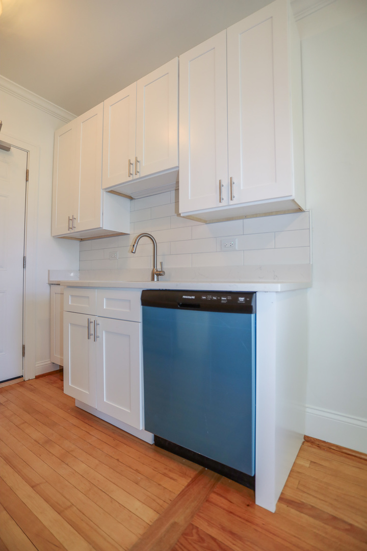 4411 North Hamilton Avenue, Unit 2W Chicago, IL 60618 - Photo 5 of 15 a kitchen with granite countertop white cabinets and a wooden floor