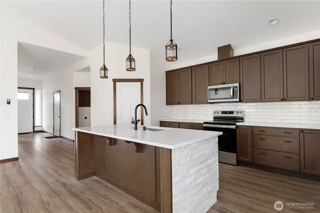 a kitchen with stainless steel appliances granite countertop a sink a stove and a wooden floors