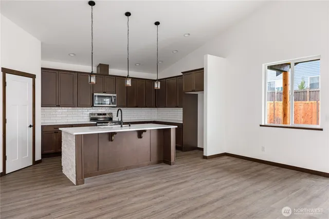 a kitchen with stainless steel appliances granite countertop a sink a stove and a wooden floors