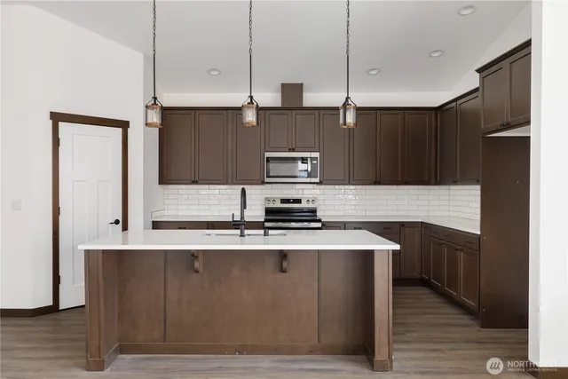 a kitchen with stainless steel appliances granite countertop a sink a stove and a refrigerator