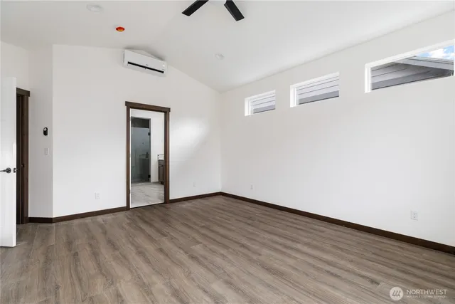 a view of an empty room with wooden floor and a ceiling fan