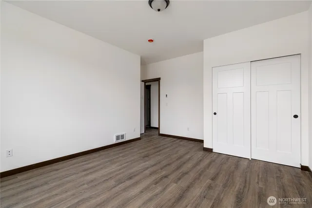 a view of an empty room with wooden floor and closet