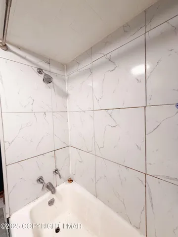 a bathroom with a white bath tub and shower