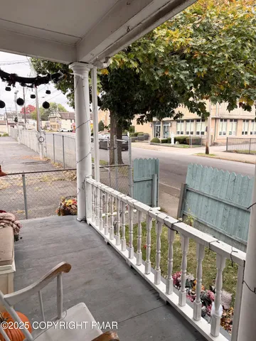 a view of a small yard with wooden fence and a large tree