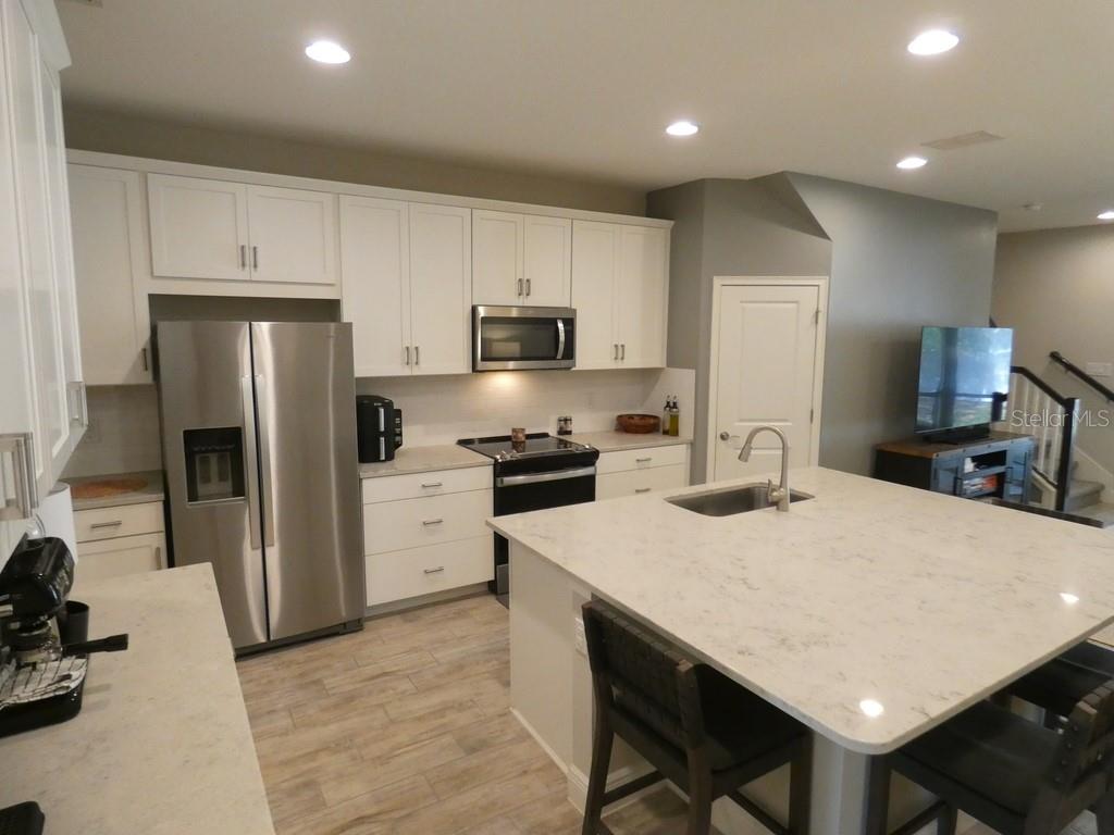 1505 Sunset Wind Loop Oldsmar, FL 34677 - Photo 3 of 36 a kitchen with a refrigerator a stove a sink a dining table and chairs