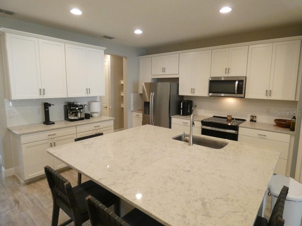 1505 Sunset Wind Loop Oldsmar, FL 34677 - Photo 7 of 36 a kitchen with stainless steel appliances a stove a sink a microwave a refrigerator and cabinets