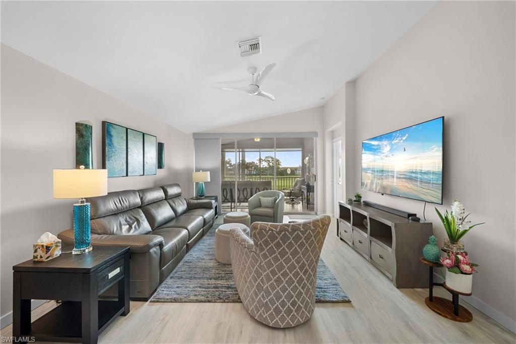Living area with ceiling fan, light wood finished floors, and lofted ceiling