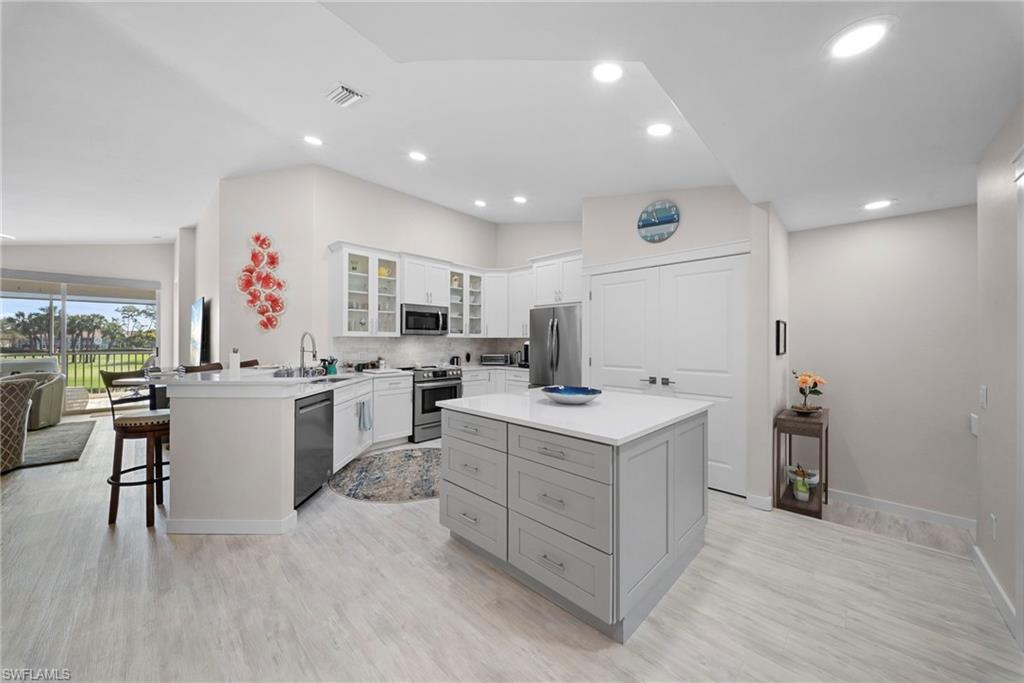 9231 Spring Run Boulevard, Unit 2109 Estero, FL 34135 - Photo 6 of 35 Kitchen featuring a peninsula, glass insert cabinets, a kitchen breakfast bar, stainless steel appliances, and decorative backsplash