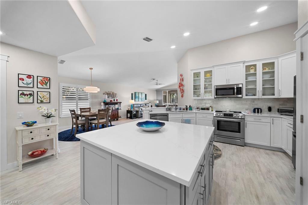 9231 Spring Run Boulevard, Unit 2109 Estero, FL 34135 - Photo 8 of 35 Kitchen featuring stainless steel appliances, a peninsula, white cabinetry, decorative backsplash, and glass insert cabinets