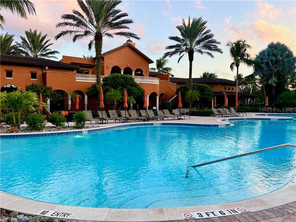 9092 Chula Vista Street, Unit 11003 Naples, FL 34113 - Photo 28 of 42 a view of a swimming pool with a lawn chairs under palm trees