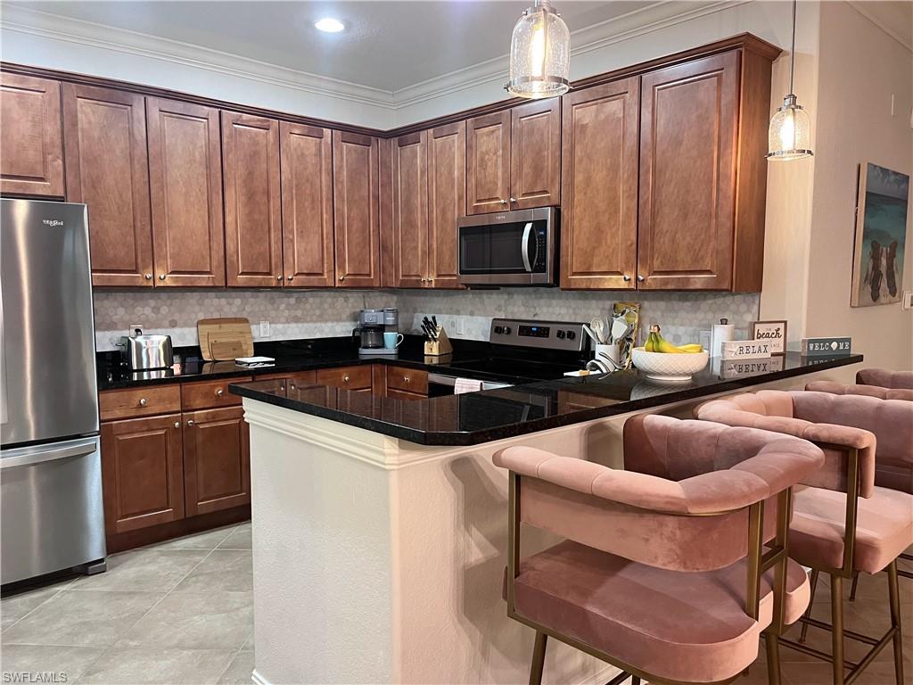 9092 Chula Vista Street, Unit 11003 Naples, FL 34113 - Photo 4 of 42 a kitchen with stainless steel appliances granite countertop a sink a stove a refrigerator cabinets and chairs