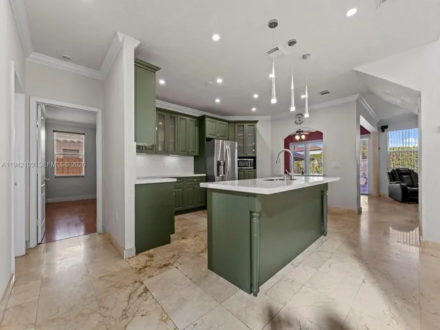 a kitchen with stainless steel appliances kitchen island granite countertop a refrigerator and a sink