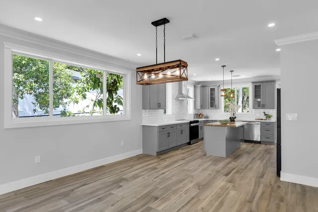 a kitchen with kitchen island granite countertop a stove a sink a center island and wooden floor