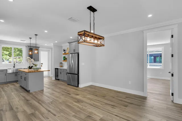 a kitchen with stainless steel appliances granite countertop a refrigerator a sink dishwasher a stove and white countertops with wooden floor