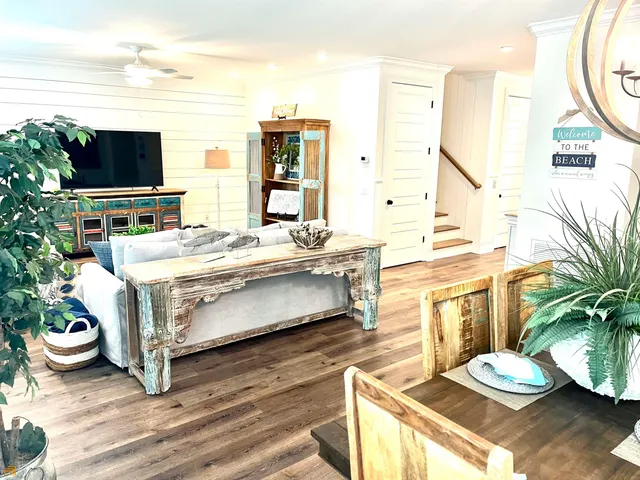 a living room with furniture a wooden floor and next to a large window