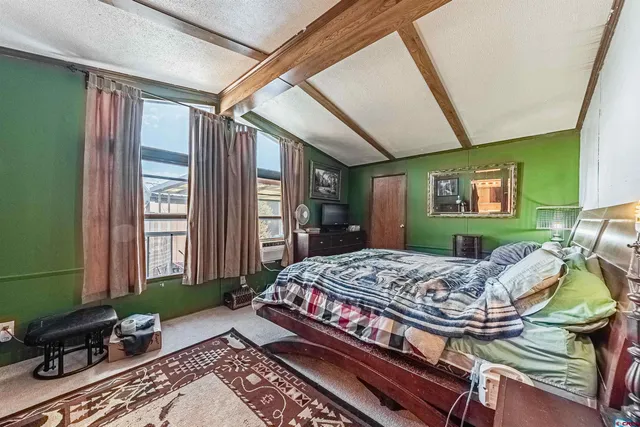 a bedroom with a bed dresser and a large window