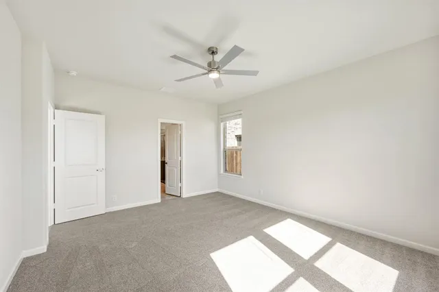 an empty room with a ceiling fan and window