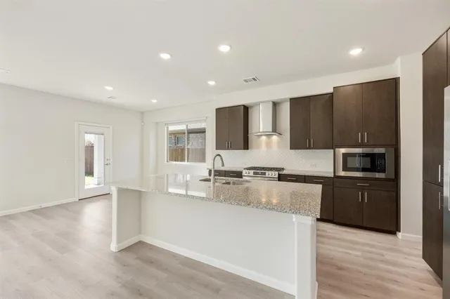 a kitchen with stainless steel appliances granite countertop a refrigerator a stove and a sink with wooden floor