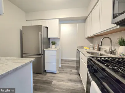 a kitchen with a white appliances wooden floors and white cabinets