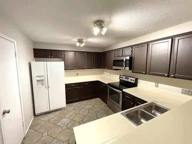 a kitchen with granite countertop a refrigerator and a sink