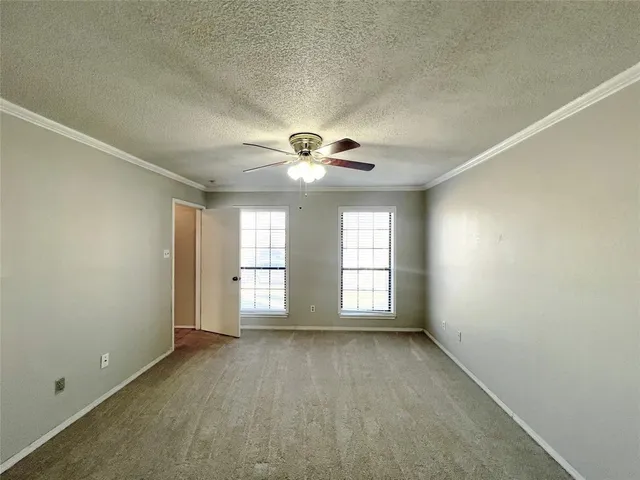 an empty room with windows and chandelier fan