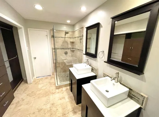 a bathroom with a sink a mirror a vanity and shower