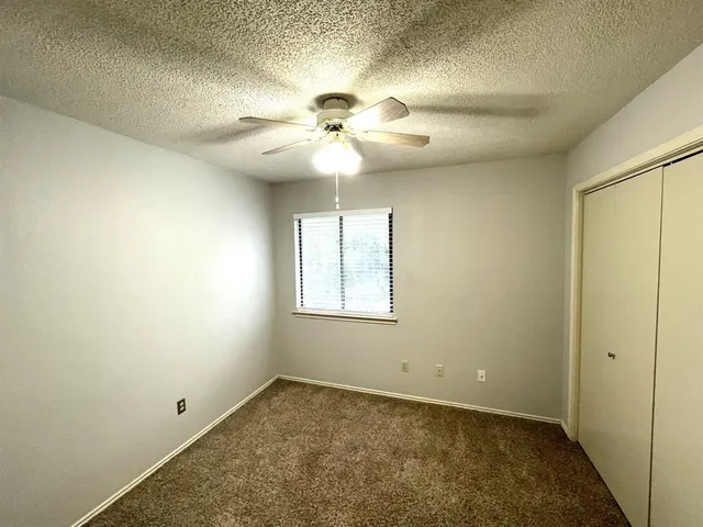 an empty room with a chandelier fan and windows