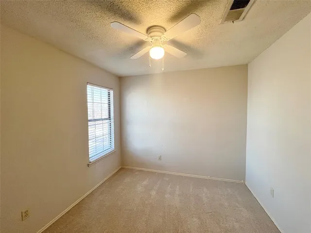 an empty room with a window and chandelier fan