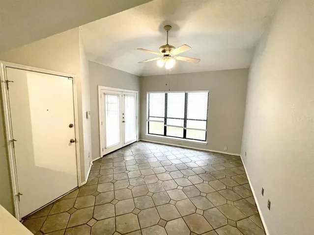 an empty room with windows and fan