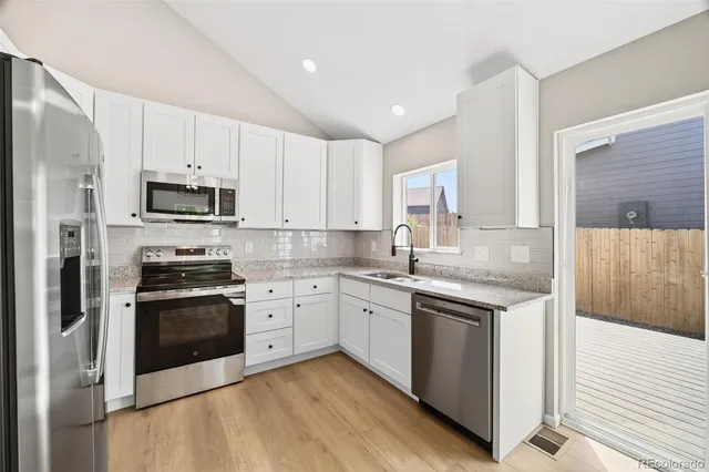 a kitchen with stainless steel appliances granite countertop a stove top oven a sink and white cabinets